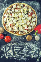 Homemade large vegetarian pizza with ingredients ready to bake on a dark table with text