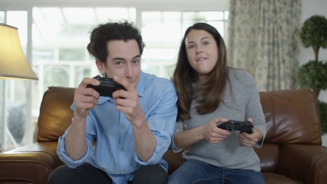  Competitive couple playing video games together at home