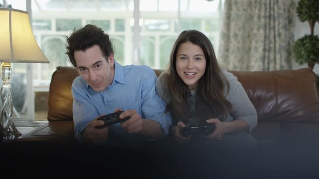  Competitive couple playing video games together at home