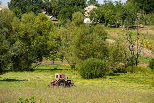 Old red tractor haying in a meadow