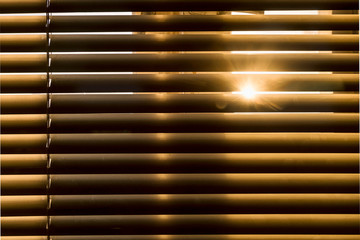 Horizontal blinds let in sunlight. Naturally warm tone. The morning sunbeam penetrates the gap between the louvres of the sun blinds.