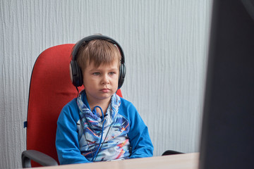 leisure, education, children, technology and people concept - boy with computer and headphones at office