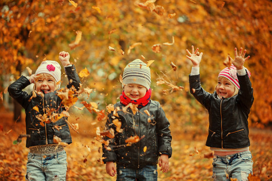 Happy kids having fun with leaves in autumn park