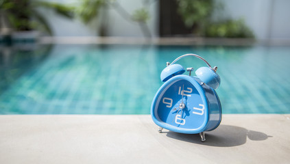 Blue clock on swimming pool edge, morning outdoor day light