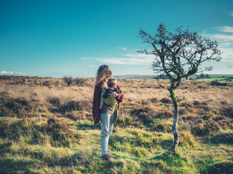 Mother with baby standing by tree in wilderness