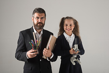 Kid and tutor hold book, pencils and microscope