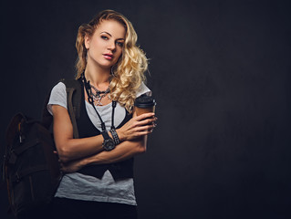 Blonde female backpacker holds a compact digital camera.