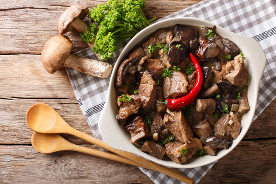 Delicious food: beef stew with wild mushrooms in spicy sauce close-up in a bowl. Horizontal top view