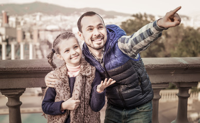smiling father and daughter pointing at sight during sightseeing tour
