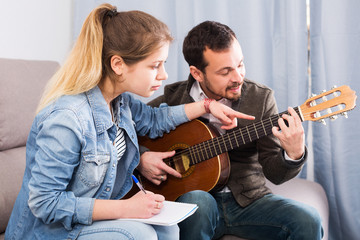Guitar tutor helping client learn instrument