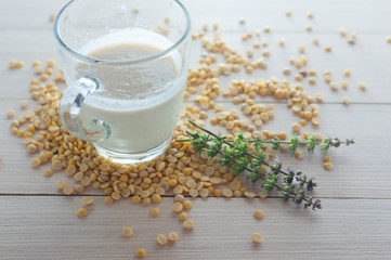 soy milk in glass with soy beans on wood plate side view