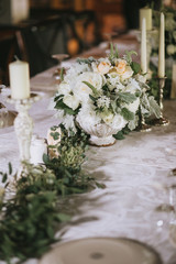 Beautiful decorated wedding table with floral white bouquets, candlesticks and a white tablecloth