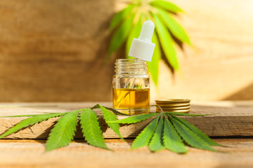 Green leaves of medicinal cannabis with extract oil on a wooden table