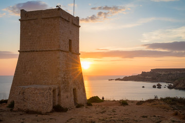 Beautiful golden sunset at Ghajn Tuffieha Tower, above Golden Bay, ancient watchtower built by the Knights of St. John, Golden Bay, Malta - obrazy, fototapety, plakaty