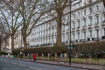 Fototapeta premium LONDON CITY - DECEMBER 24, 2016: Red mail box standing on Westbourne Terrace in front of a white residential building