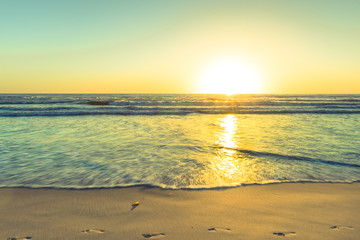 The bright sun of California. Footprints on the sand of the beach. Sunset bright sun sets over the...