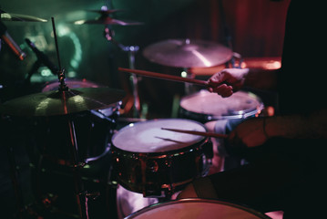 Drummer playing his drum kit on concert in club