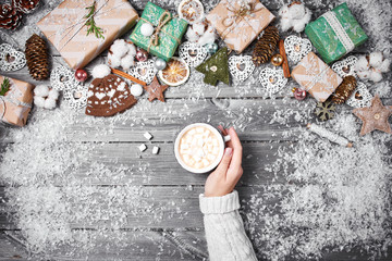 Hands holding a cozy mug with sweet holiday food. Winter and Christmas time concept.