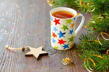Christmas black tea in mug with multicolored stars and Christmas decor
