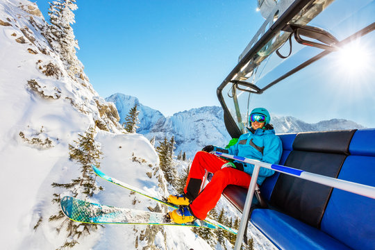 Skier sitting at ski lift in high mountains during sunny day