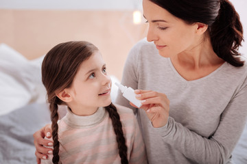 Loving woman giving nasal drops to a smiling child