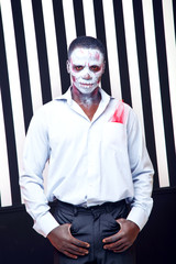 African man a striped background. White and black bands as a symbol of good and evil, good and bad. Zebra. Fashion man in the role of zombie or voodoo. Stylish african man. Halloween. Party, Carnival.