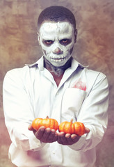 Human skeleton holding two pumpkins in his hands. the character at Halloween. Man holding a pumpkin...