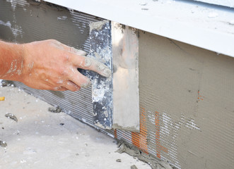 Contractor plastering foundation wall after rigid syrofoam insulation for house energy saving.