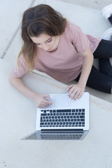 Teenage girl sitting on a ladder with her laptop.