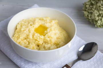 Millet porridge and melting butter in white bowl. Selective focus. Closeup.