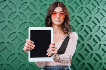 Woman in sunglasses showing tablet computer