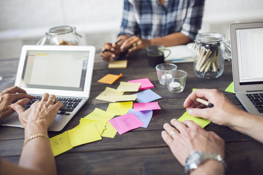 Three coworkers working using laptop and post-it notes