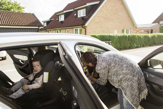 Mother fastening son's (18-23 months, 0-1 months) seat belt