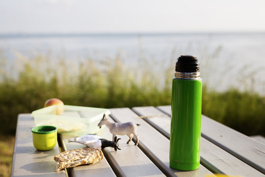 Insulated drink container and toys on picnic table