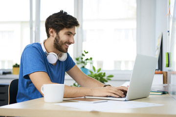 Smiling student using laptop at home