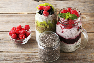 Chia pudding with berries in glass jars on wooden table