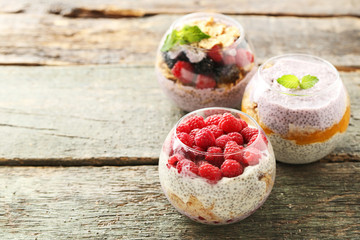 Chia pudding with berries in glasses on wooden table