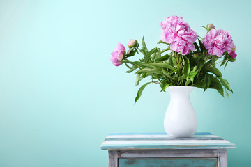 Bouquet of peony flowers in vase on mint background