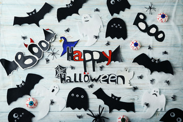Halloween ghosts, bats and spiders on white wooden table