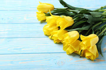 Bouquet of yellow tulips on a blue wooden table
