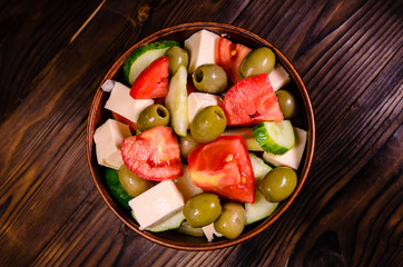 Greek salad in a bowl on wooden table. Top view