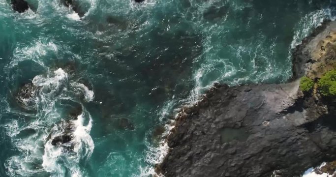 Aerial top down drone view of waves hitting rocks and small island