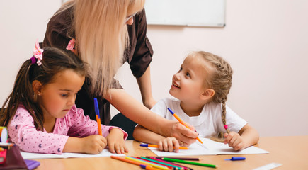 Fototapeta premium two happy little schoolgirls study in class, the teacher explains