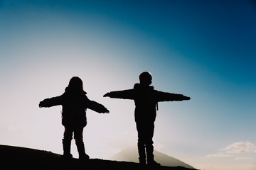 Fototapeta na wymiar Silhouettes of little boy and girl hiking in sunset