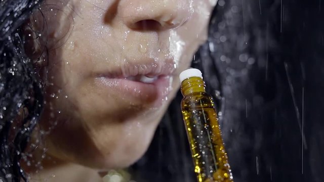 woman is enjoying of amazing smell of expensive perfume, standing under rain, close-up shot of lips