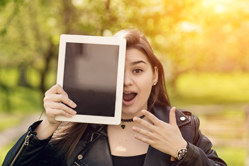 Beautiful caucasian girl in black leather jacket. Young woman holding a tablet