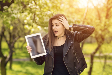 Beautiful caucasian girl in black leather jacket. Young woman holding a tablet