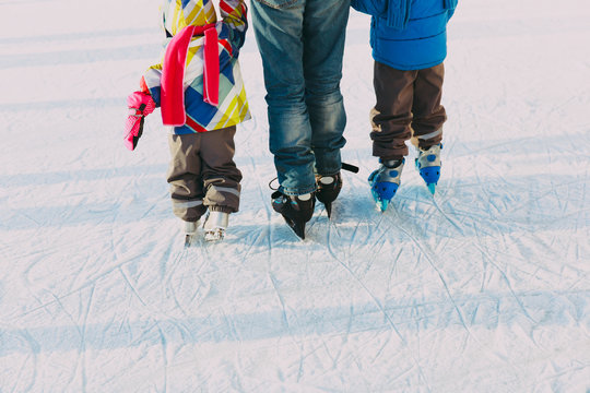 father teaching two kids to skate in winter