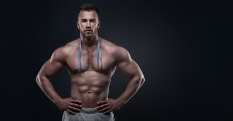 Fototapeta na wymiar Muscular man with measurement tape