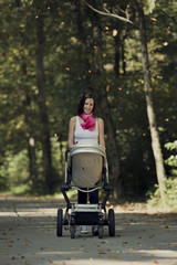 Fototapeta na wymiar Attractive stylish woman pushing a baby stroller